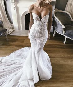 a woman in a white wedding dress standing on a wooden floor next to a fireplace