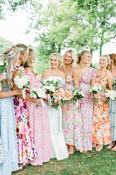 a group of women standing next to each other wearing dresses and holding bouquets in their hands