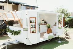 an old trailer converted into a house with plants growing out of the windows and doors