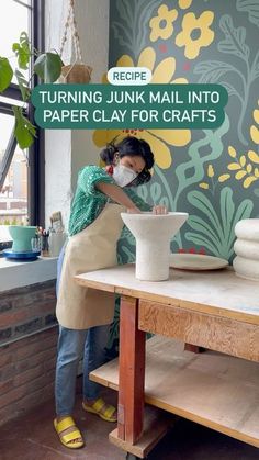 a woman in green shirt and white apron making paper clay