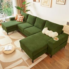 a living room with a large green couch and white rugs on the wooden floor