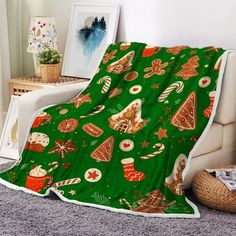 a green blanket with christmas decorations on it sitting next to a white chair in a living room