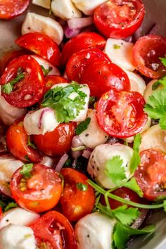 a white bowl filled with tomatoes, onions and parsley on top of a wooden table