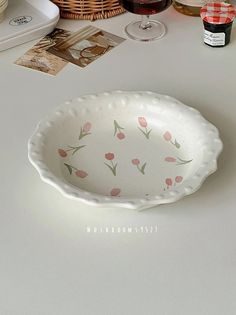 a white bowl with pink flowers on it sitting on a table next to other dishes