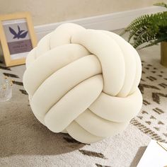 a large white ball sitting on top of a rug next to a potted plant