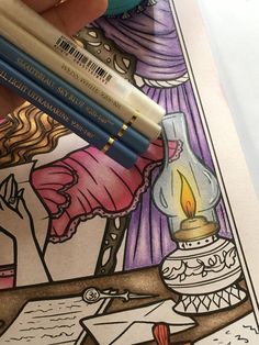 two colored pencils sitting on top of a coloring book with an image of a lamp