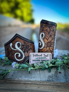 two wooden boxes sitting on top of a table next to leaves and flowers with the letter s painted on them