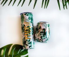 two canisters sitting on top of a table next to a green leafy plant