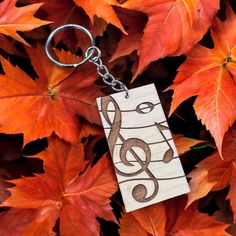 a wooden keychain with musical notes on it sitting in front of some leaves