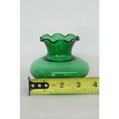 a green vase sitting next to a measuring tape