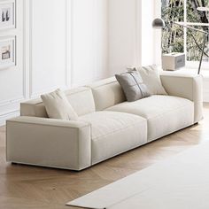 a living room with white walls and wood flooring is pictured in this image, the couch has two pillows on it