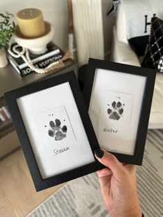 two framed pictures with the same dog's paw prints on them, one is black and white