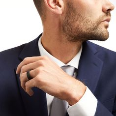 a man in a suit adjusts his ring on his finger while looking off to the side