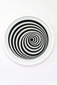 a white plate with black and white swirls on the center, in front of a white wall