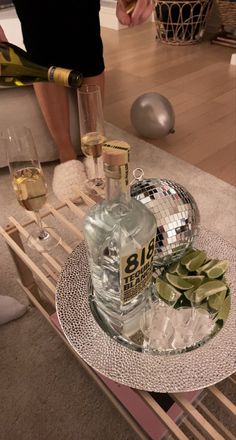 a table topped with a bottle of alcohol and two glasses filled with ice cubes