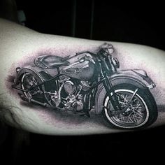 a black and white photo of a motorcycle tattoo on the left upper half of the arm