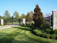 a gated driveway leading into a lush green yard