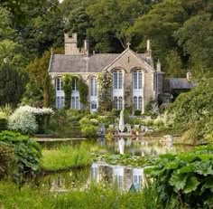 an old house surrounded by greenery and water features a pond in the foreground