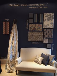 a white couch sitting in front of a blue wall with different types of fabric on it