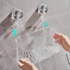 two hands are holding the handles to a water faucet that is attached to a wall