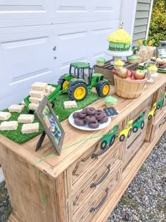 a table topped with cookies and desserts on top of a grass covered field next to a garage