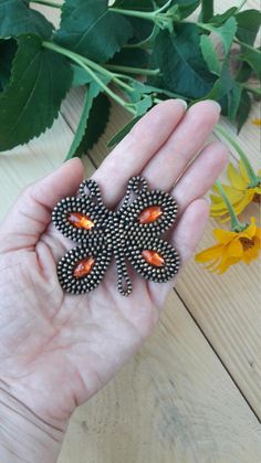 a person is holding some kind of flower brooch in their left hand and yellow flowers on the right