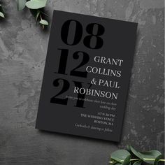 a black and white wedding card with the number two on it, surrounded by greenery