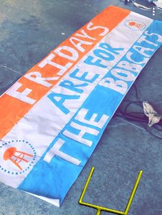 an orange, white and blue banner is laying on the ground next to a yellow pole