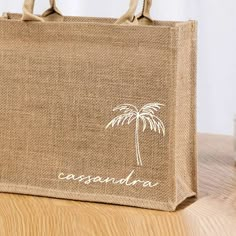 a burlap shopping bag with a palm tree on the front and white writing