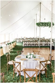 a large tent with tables and chairs set up for an outdoor wedding reception in the grass