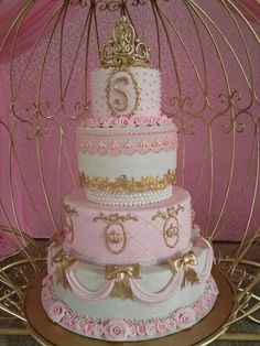 a three tiered cake with pink and gold decorations