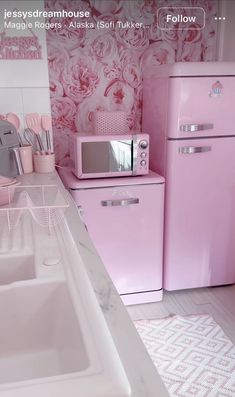 a kitchen with pink appliances and wallpaper