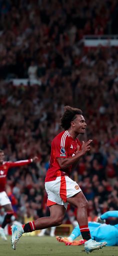 a soccer player is running on the field in front of an audience and holding his arms out