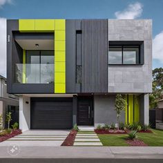 a modern house with yellow and grey accents on the front, green doors and windows