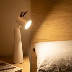 a bed with a lamp on top of it next to a night stand and book