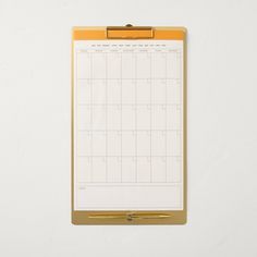 a clipboard with a calendar attached to it on a white wall next to a pen