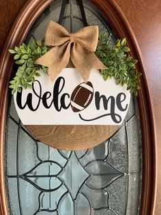 a welcome sign with a football on it and a bow hanging from the front door