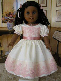 the doll is wearing a white and pink dress