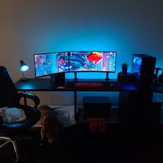 a computer desk with two monitors and a cat sleeping on the chair next to it