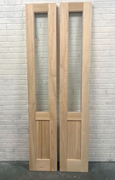 two wooden doors sitting next to each other in front of a white brick wall and floor