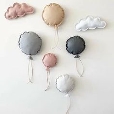 four different colored clouds hanging from strings on a white wall in the shape of balloons