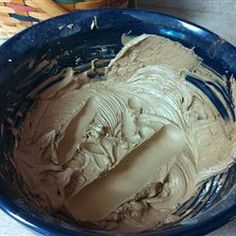 a blue bowl filled with chocolate frosting on top of a table