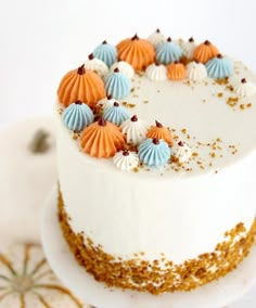 there is a white cake with orange and blue decorations on it