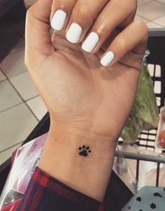 a woman's hand with a small dog paw tattoo on her left inner wrist