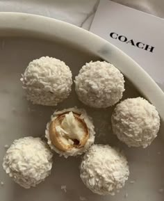 four coconut balls sitting on top of a white plate next to a paper that says coach