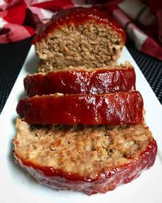 two slices of meatloaf on a white plate with a red ribbon around it