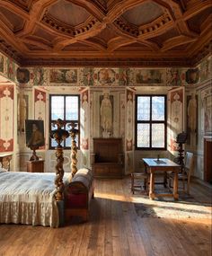 an ornate bedroom with wood floors and painted walls, along with paintings on the walls