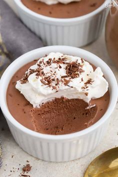 two white bowls filled with chocolate pudding and whipped cream