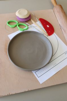 a bowl with scissors and other crafting supplies on top of a piece of paper