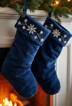 two blue christmas stockings hanging from a mantel